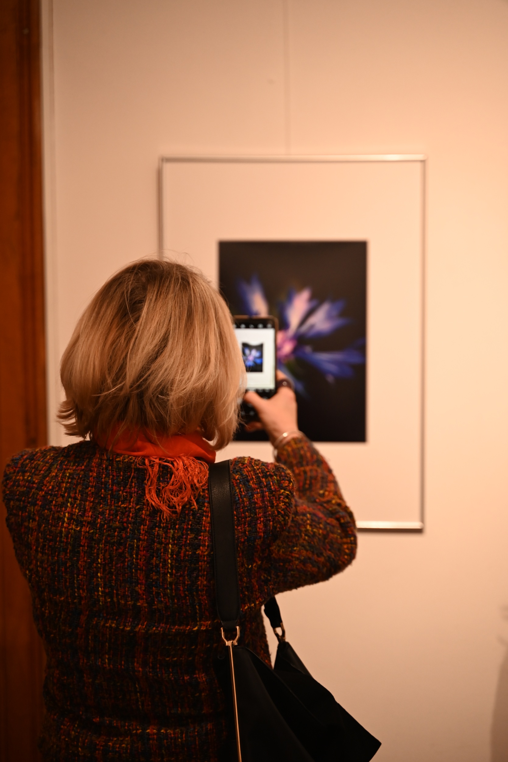 Kobieta fotografująca telefonem zdjęcie w ramie - części wystawy.