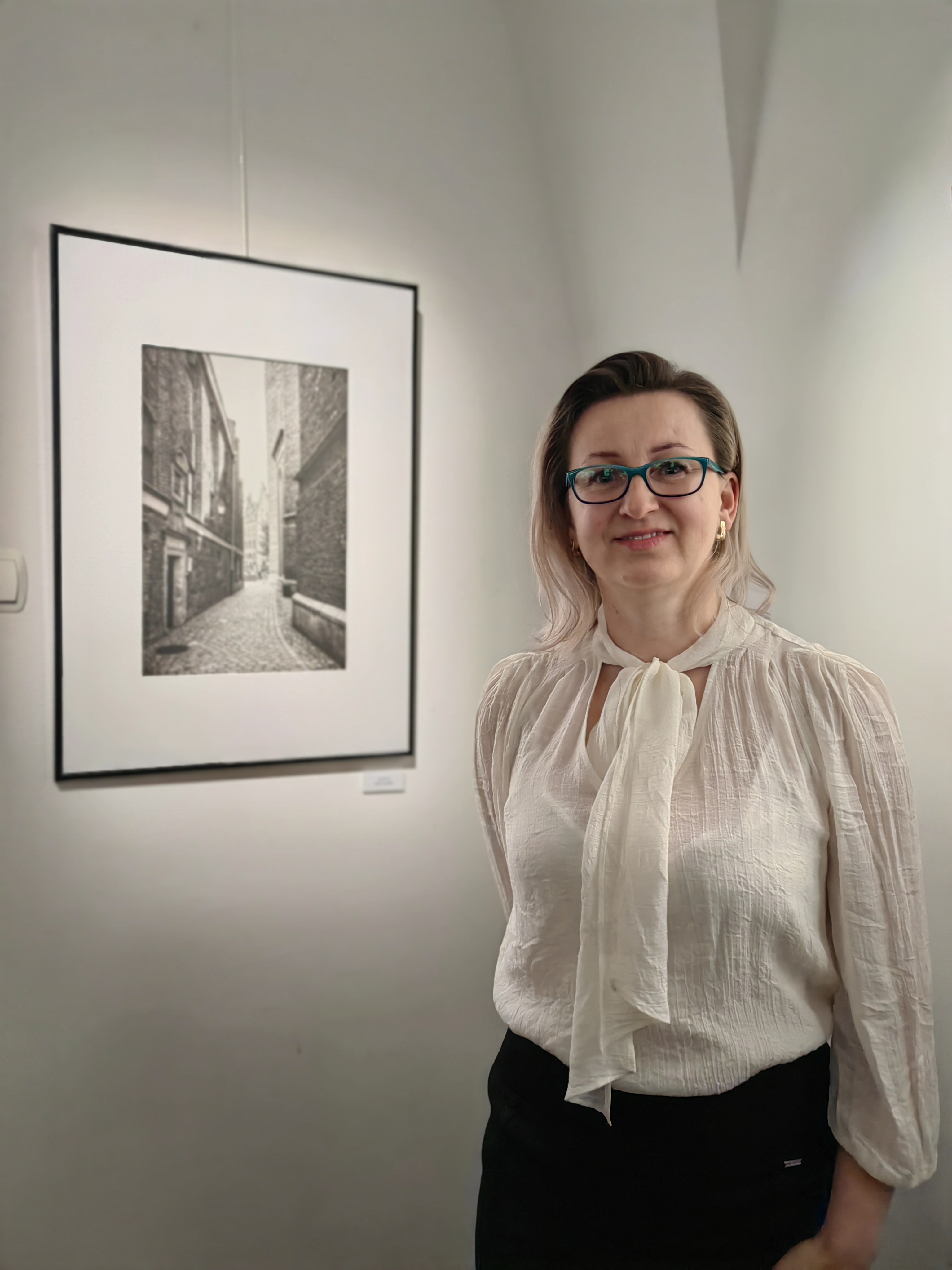 Uśmiechnięta Monika Frys-Żurek obok swojej fotografii Gdańska Starówka